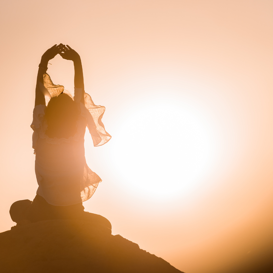 femme les mains au ciel face au soleil